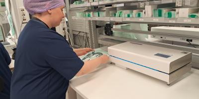 Kuvassa välinehuoltokeskus ja siellä välinehuoltajaopiskelija käyttämässä laitetta nimeltä kuumasaumain.