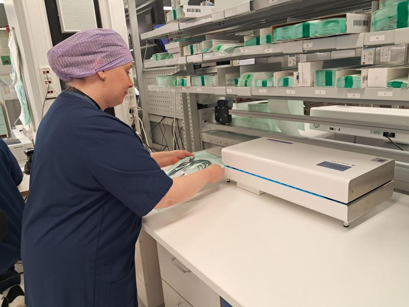 Kuvassa välinehuoltokeskus ja siellä välinehuoltajaopiskelija käyttämässä laitetta nimeltä kuumasaumain.